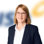 A woman with shoulder-length light brown hair in a navy blazer and glasses, smiling at the camera.
